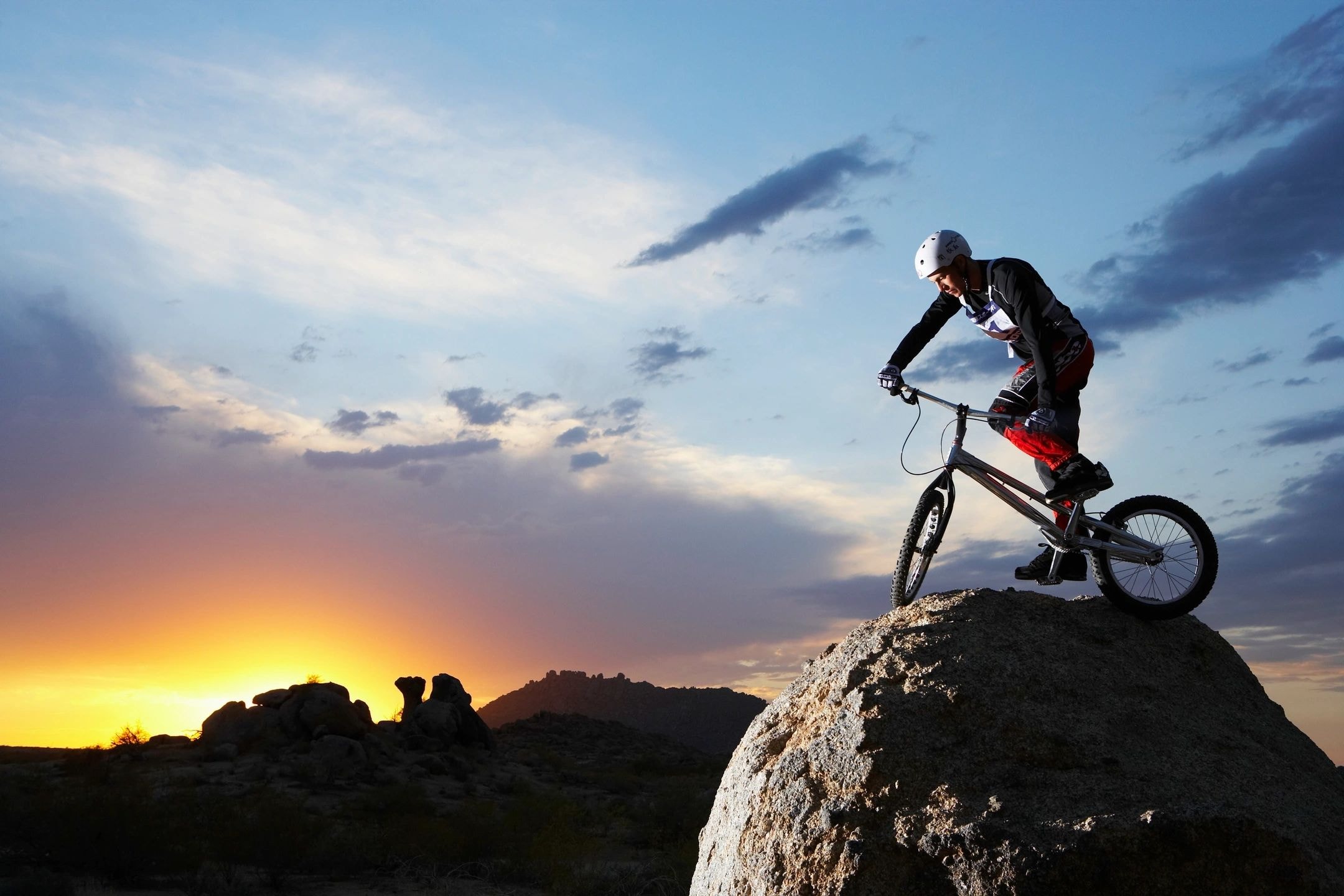 Mountain biker at sunset on a rocky boulder